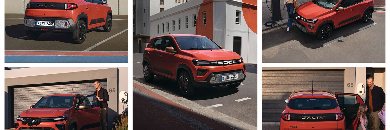 Ein orange-roter Dacia der auf einem Parkhausdach in einer Metropole parkt neben einer E-Ladesäule.